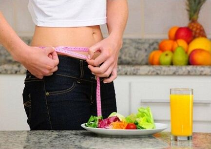 A girl who loses weight through diet measures her waistline